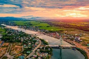 Khung cảnh đô thị phát triển ven sông, tượng trưng cho việc kiến tạo giá trị thực và phát triển bền vững trong ngành du lịch, như con đường cho du lịch Đại Nam Việt Nam.