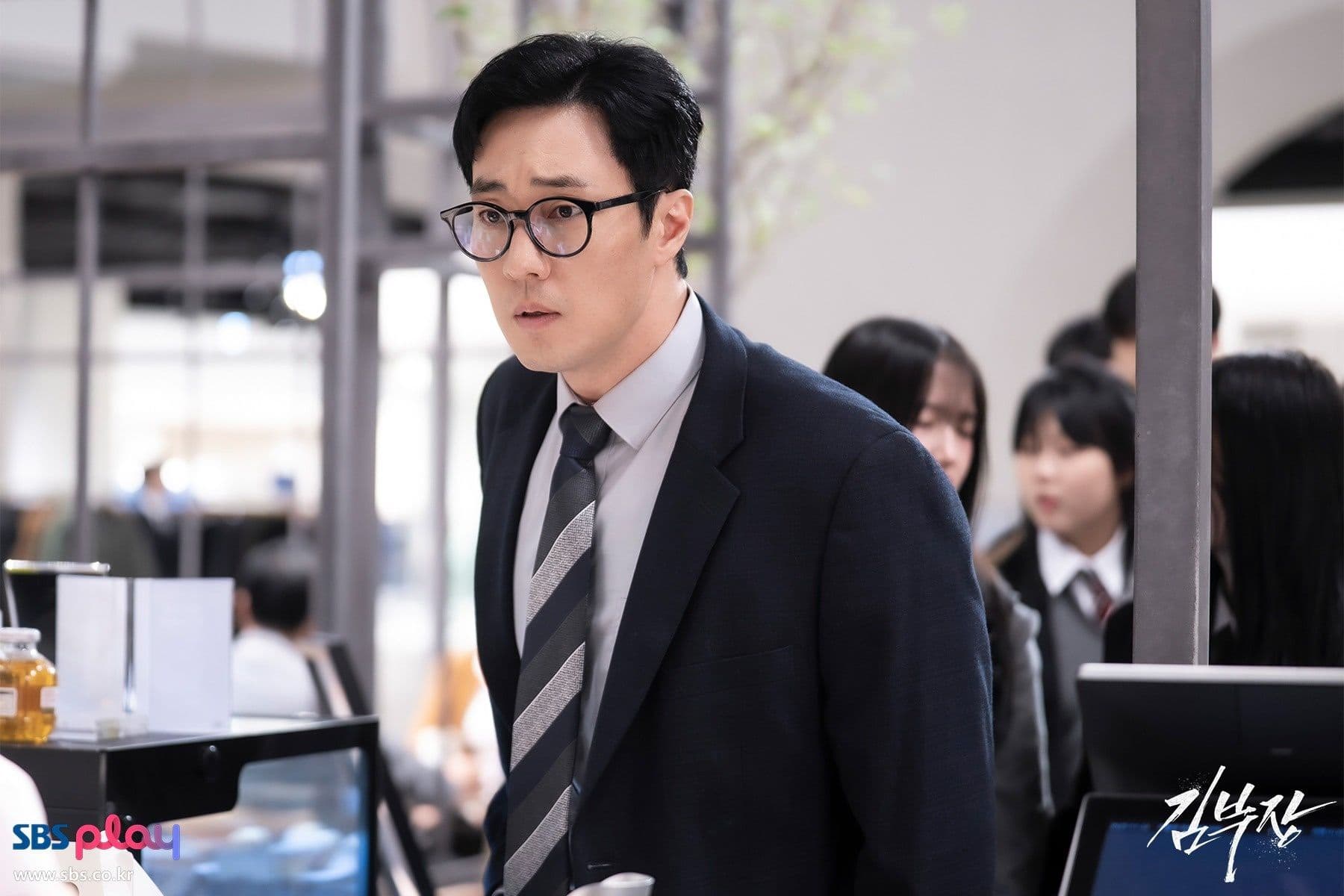 Kim Do Hyun (So Ji Sub) với vẻ mặt lo lắng, đeo kính, trong vai nhân viên văn phòng cam chịu ở quá khứ của 'Đặc vụ Kim tái khởi động'.