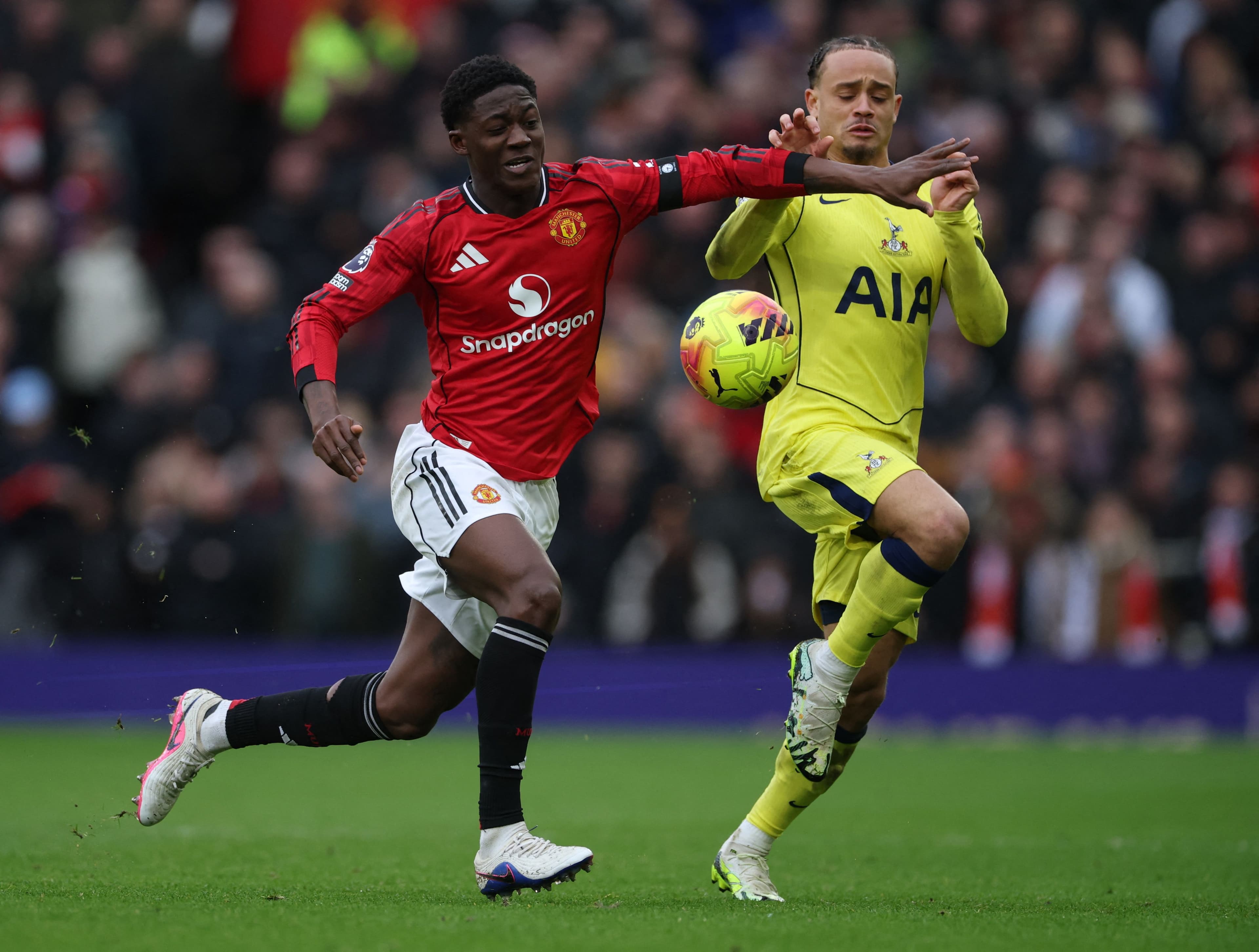 Kobbie Mainoo tranh bóng với cầu thủ Tottenham, minh họa cho sự trở lại mạnh mẽ