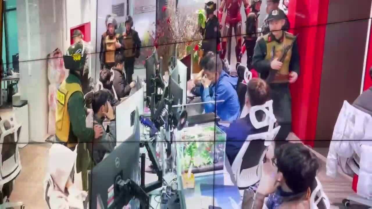 Lực lượng chức năng đột kích một văn phòng, nơi các cá nhân đang làm việc trên máy tính, minh họa mạng lưới tinh vi của Xôi Lạc TV.