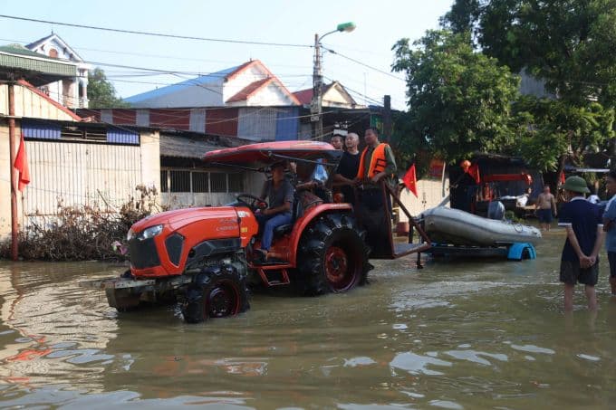 Lực lượng cứu hộ dùng máy kéo và thuyền hỗ trợ người dân Đa Phúc vượt lũ