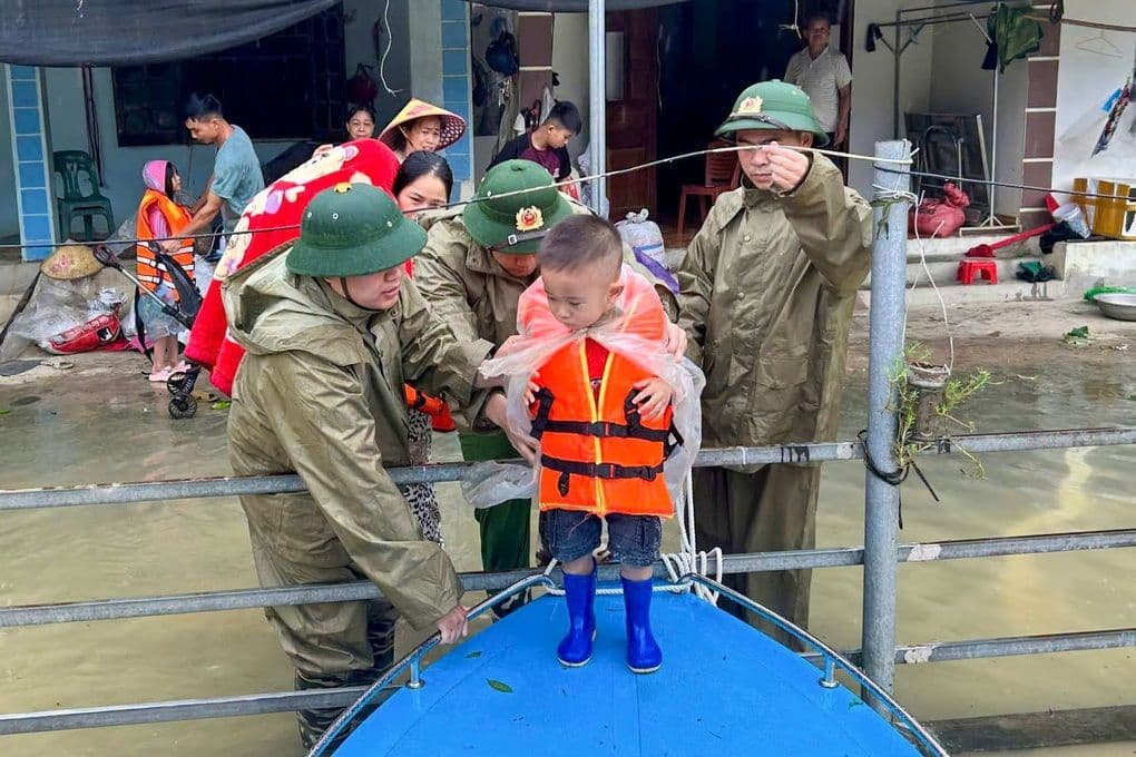 Lực lượng cứu hộ giúp đỡ người dân, bao gồm một em nhỏ mặc áo phao, trong vùng bị ngập lụt do bão số 4 gây ra.