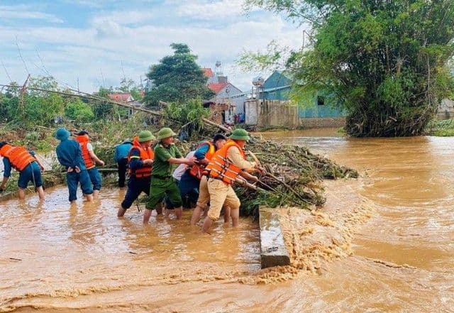 Lực lượng cứu hộ và người dân ứng phó với lũ lụt sau bão, dọn dẹp cây đổ và rác thải trên dòng nước chảy xiết.