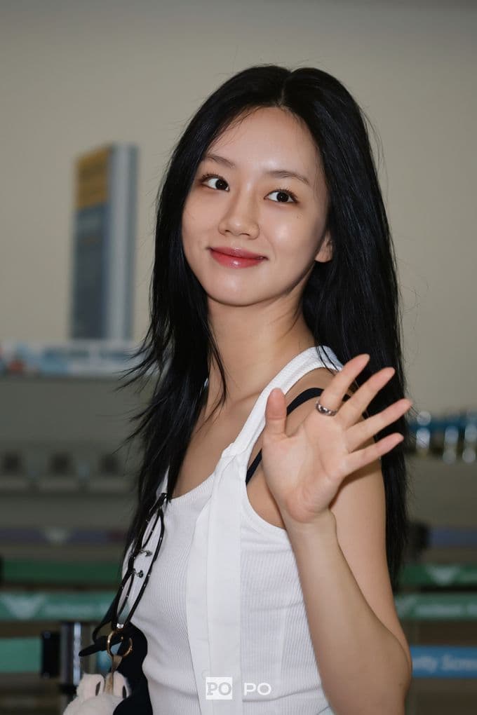 Lee Hyeri tươi cười vẫy tay chào người hâm mộ tại sân bay.
