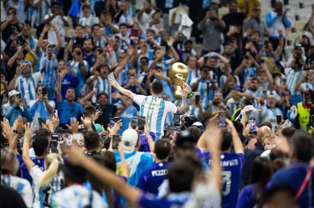 Lionel Messi ăn mừng cùng cúp vàng World Cup giữa biển người hâm mộ, tượng trưng cho đỉnh cao và tham vọng của giải đấu.