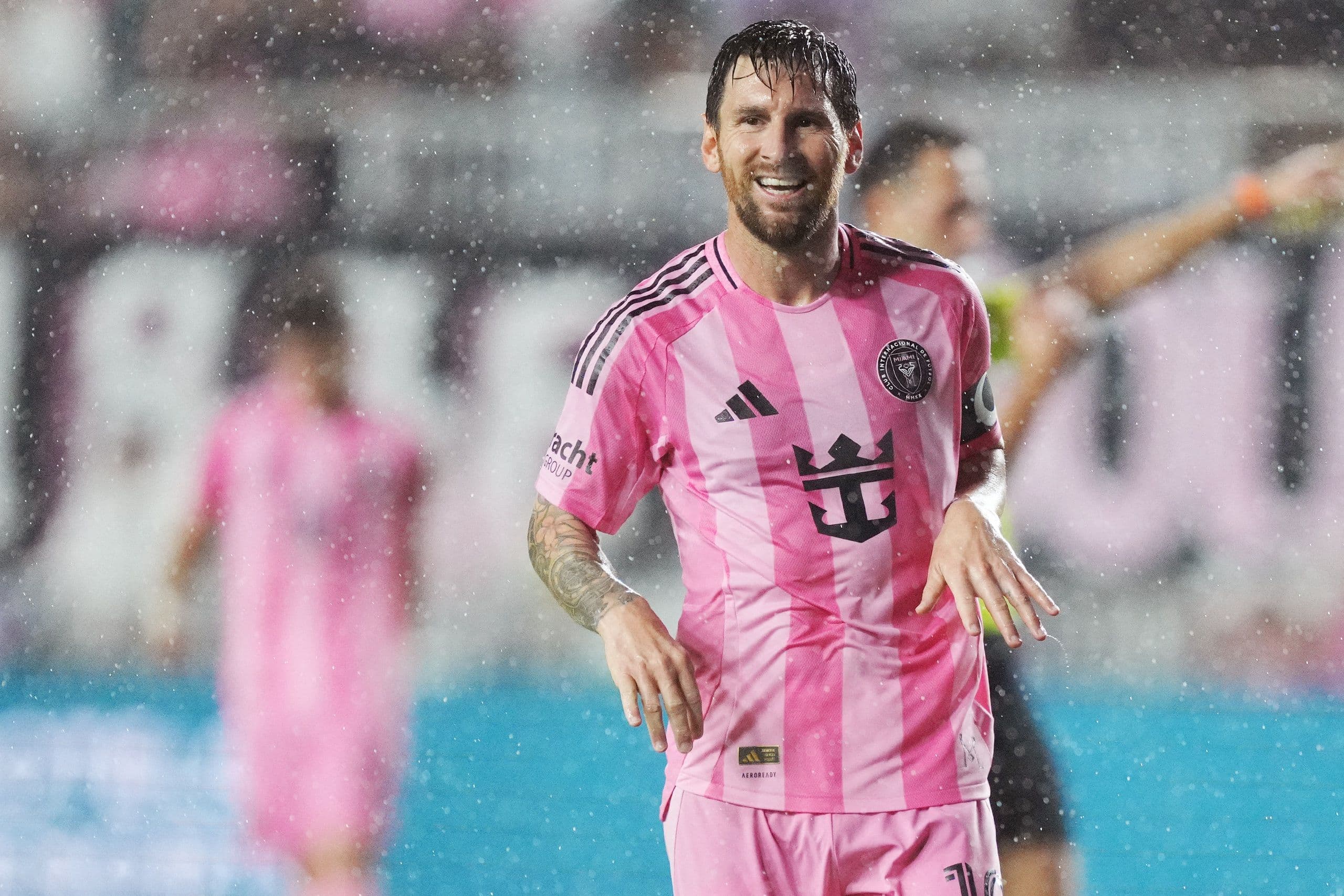 Lionel Messi trong màu áo hồng của Inter Miami trên sân cỏ, mỉm cười dưới mưa, biểu tượng cho hy vọng phá vỡ lời nguyền hòa.