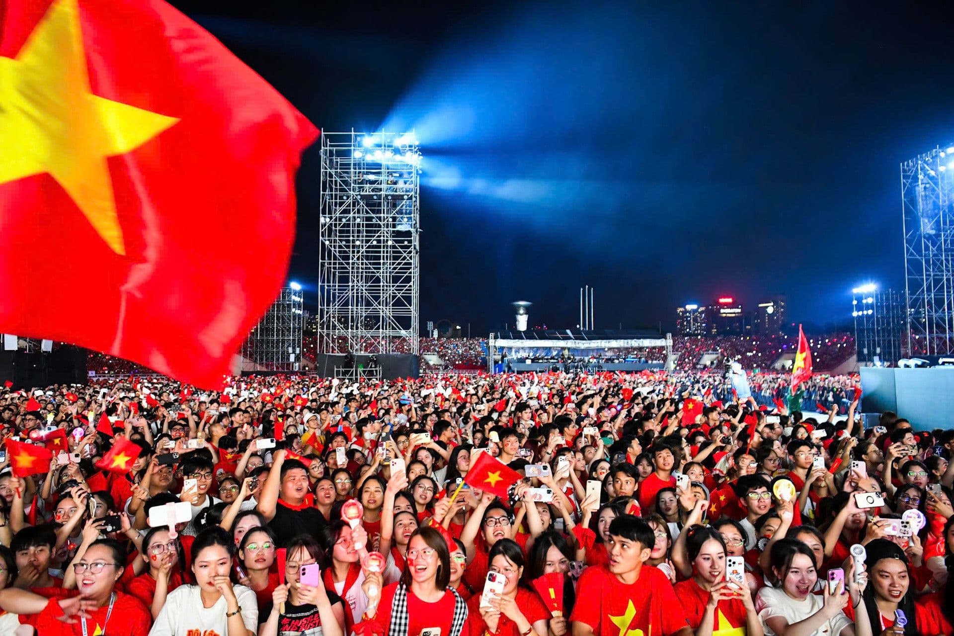 Đám đông khán giả cuồng nhiệt tại một concert lớn, nhiều người cầm cờ Việt Nam, thể hiện sức sống của thị trường âm nhạc.