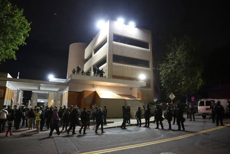 Đám đông người biểu tình và lực lượng chức năng vào ban đêm, thể hiện sự hội ngộ thách thức và phản ứng của công luận trước các sự kiện nóng.