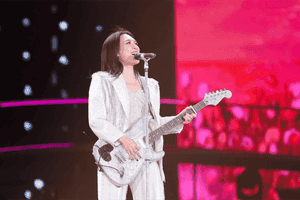 Mỹ Tâm trình diễn trên sân khấu với cây đàn guitar, thể hiện tài năng và sự nghiệp âm nhạc bền vững của cô.
