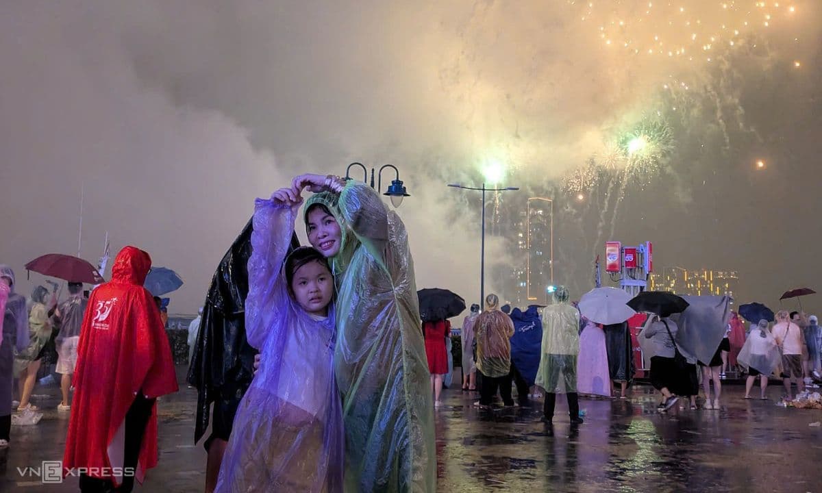 Mẹ và bé vui vẻ đội mưa xem pháo hoa tại Vũng Tàu, thể hiện tinh thần kiên cường của người dân.