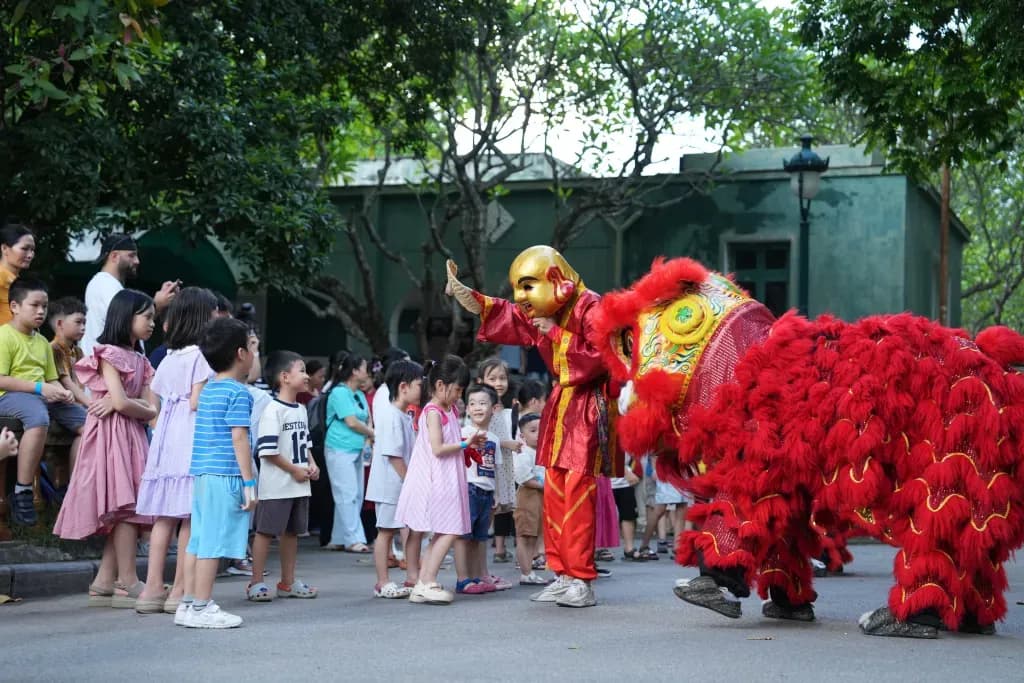 Múa lân và Ông Địa tương tác với trẻ em trong lễ hội tại Bảo tàng Dân tộc học Việt Nam.
