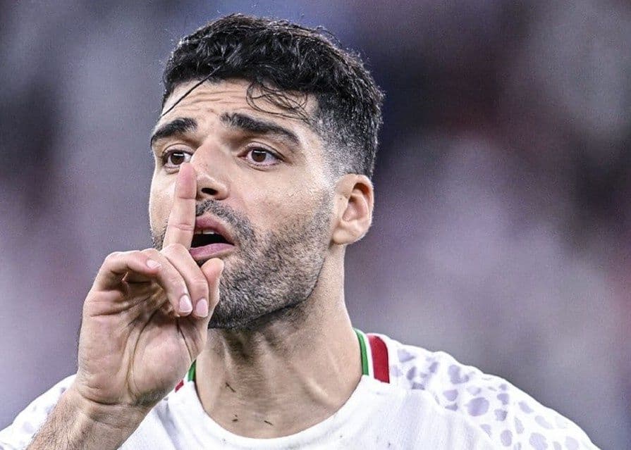 Mehdi Taremi, cầu thủ Iran, với cử chỉ đặt ngón tay lên môi, thể hiện sự quyết tâm hoặc thông điệp mạnh mẽ.