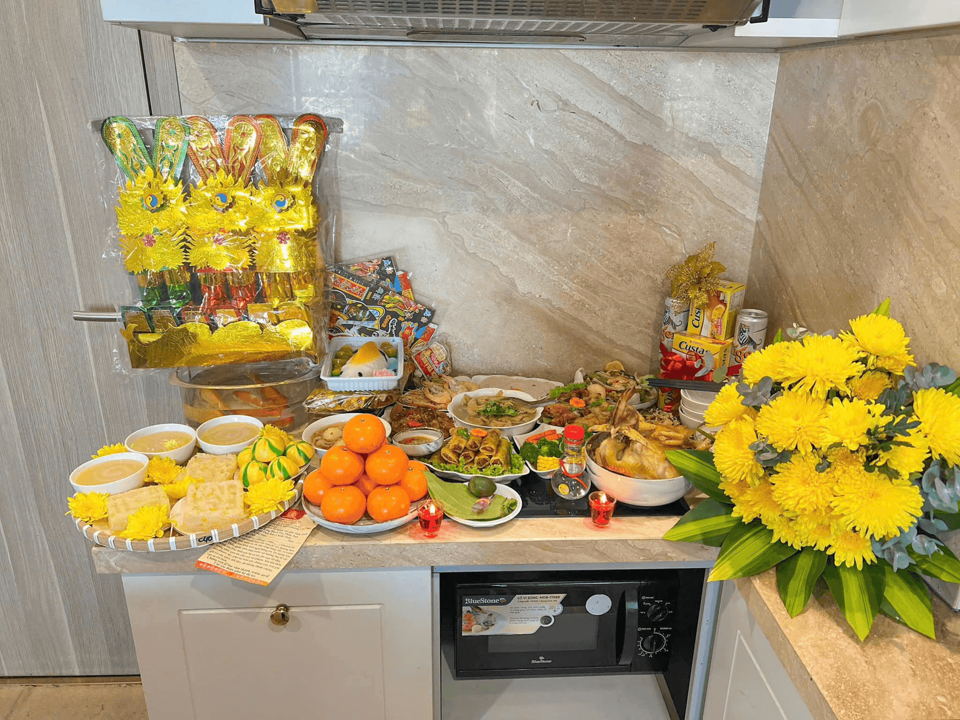 Mâm cúng ông Công ông Táo đầy đủ các món truyền thống như gà luộc, xôi, trái cây trên bàn bếp hiện đại