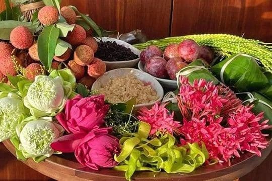 Mâm lễ vật với hoa sen hồng, vải thiều và xôi, thể hiện sự chuẩn bị tinh tế cho không gian thờ cúng và tâm hồn trong ngày Mùng 1.