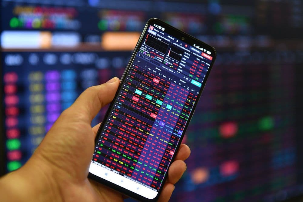 Màn hình điện thoại hiển thị dữ liệu thị trường chứng khoán, thể hiện sự luân chuyển dòng tiền giữa các kênh đầu tư.