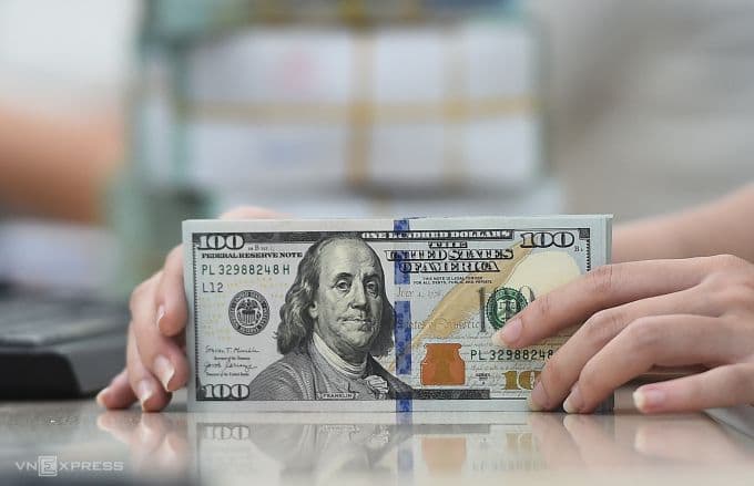 Một bó tiền đô la Mỹ được giữ bởi bàn tay, tượng trưng cho sức mạnh và sự ổn định của đồng USD.