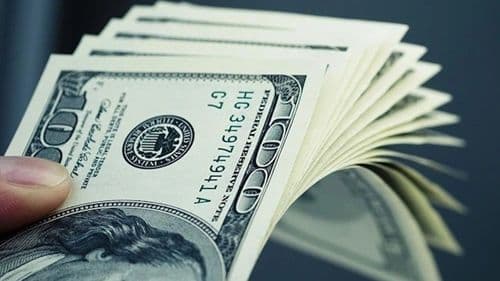 Một bàn tay đang cầm những tờ đô la Mỹ, tượng trưng cho hoạt động giao dịch và quản lý ngoại tệ