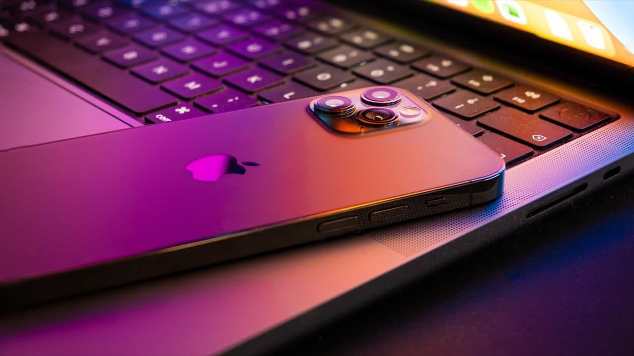 Một chiếc iPhone đặt trên bàn phím MacBook, tượng trưng cho sự tích hợp và mở rộng của iPhone 17e trong hệ sinh thái Apple.