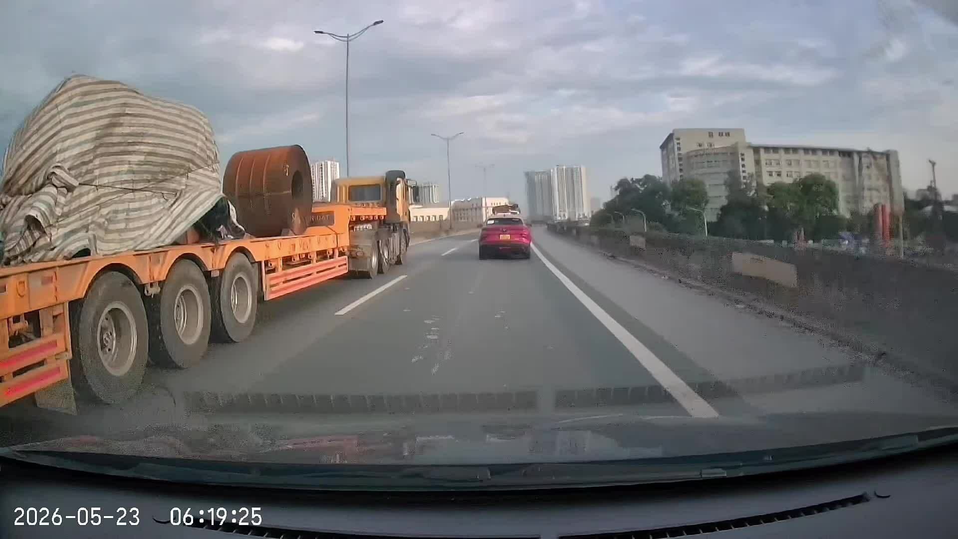 Một chiếc ô tô con suýt va chạm với xe đầu kéo chở hàng hóa cồng kềnh, thể hiện rủi ro từ văn hóa vận tải thiếu an toàn