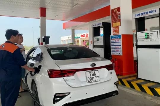 Một chiếc ô tô màu trắng đang được đổ xăng tại trạm, thể hiện thói quen tiêu dùng và quyết định của người dân trước biến động giá xăng dầu.