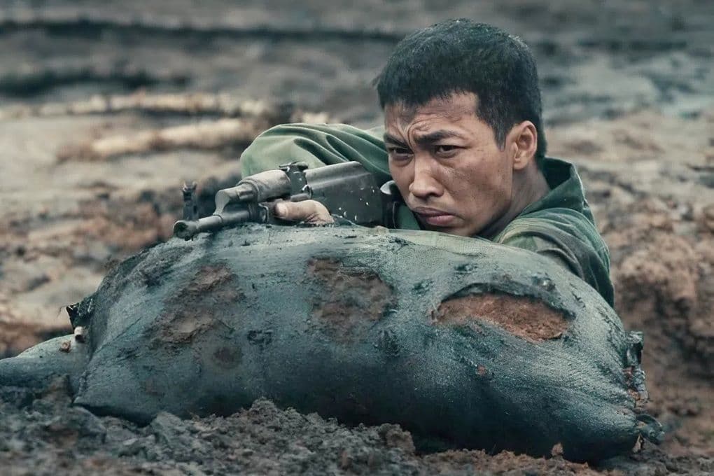 Một chiến sĩ trong phim 'Mưa Đỏ' đang chiến đấu trên chiến trường, tượng trưng cho chủ đề lịch sử bi tráng của bộ phim.