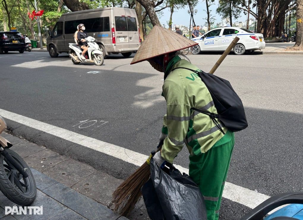 Một công nhân vệ sinh đang làm việc bên Hồ Gươm, biểu tượng cho nhịp sống thường ngày