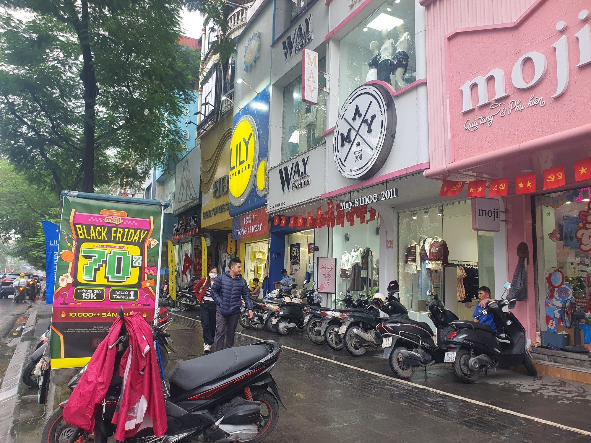 Một con phố mua sắm sầm uất với nhiều cửa hàng treo biển giảm giá lớn, minh họa cho khởi đầu của 11/11 như một ngày hội mua sắm.