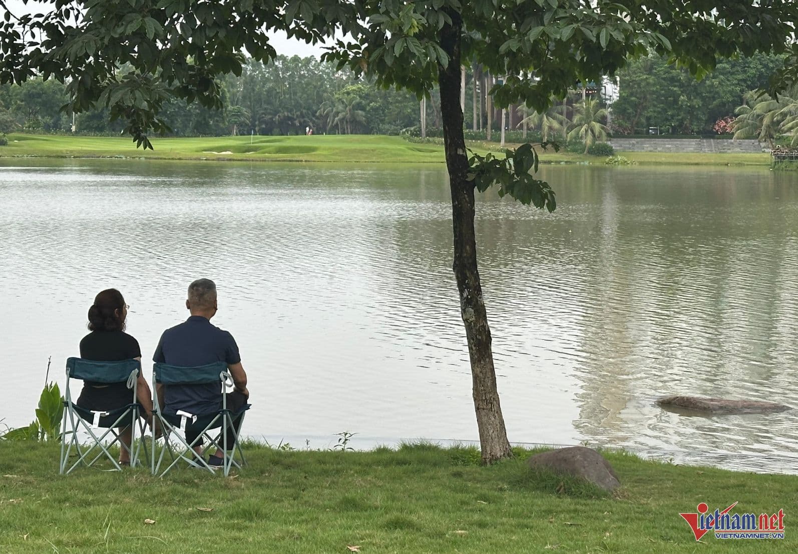 Một cặp đôi lớn tuổi ngồi bên hồ nước yên bình, tượng trưng cho 'nếp nhà an yên' và hạnh phúc gia đình.