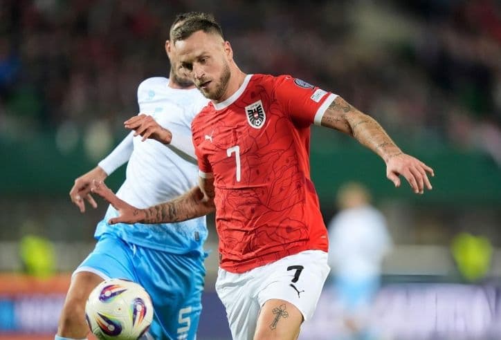 Một cầu thủ bóng đá trong trang phục đỏ đang thi đấu, tượng trưng cho áp lực ghi bàn của hàng công Nhật Bản.