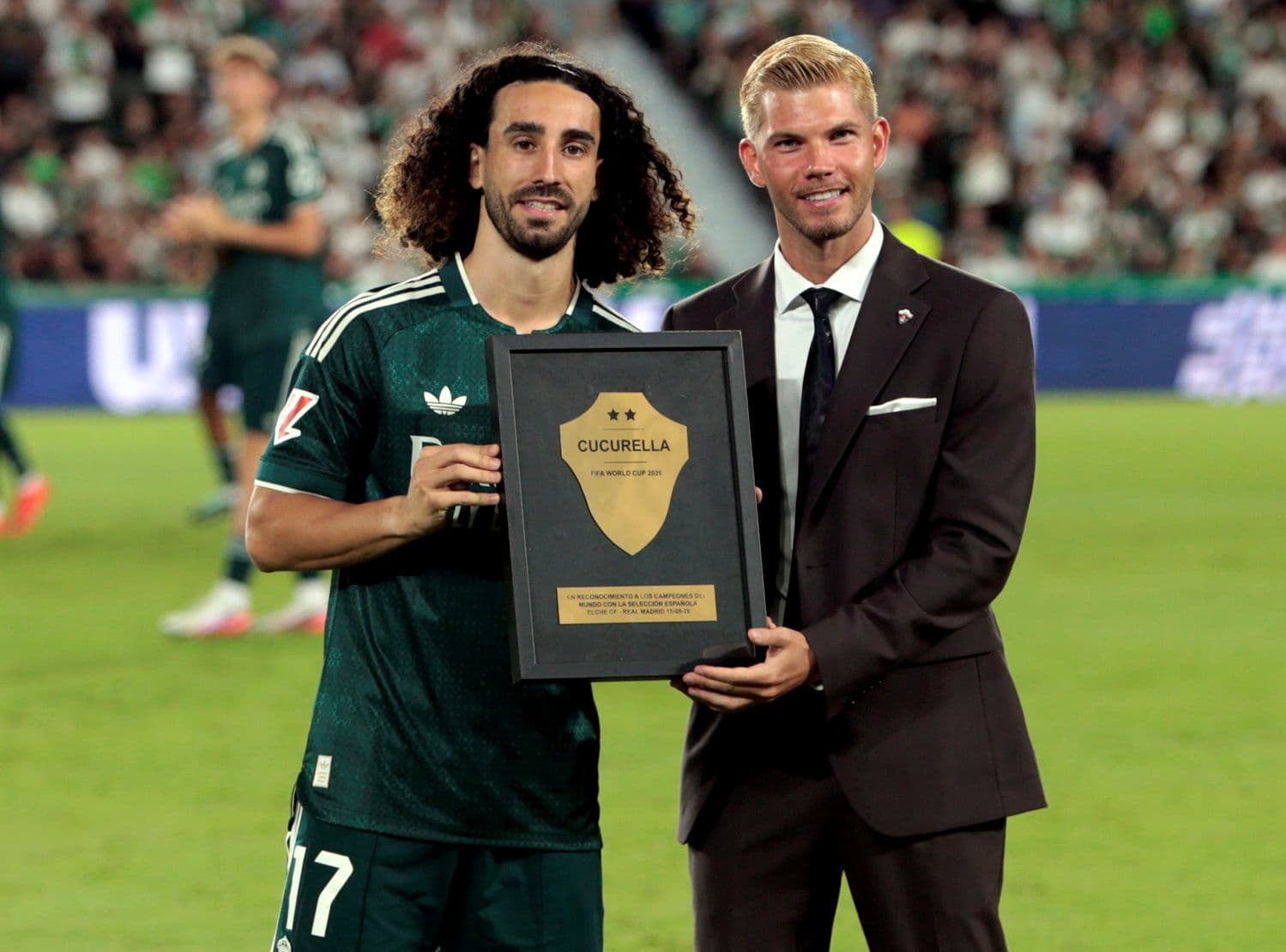 Một cầu thủ Real Madrid nhận giải thưởng từ giám đốc câu lạc bộ, biểu tượng cho di sản vĩnh cửu và cam kết về sự xuất sắc của đội bóng.