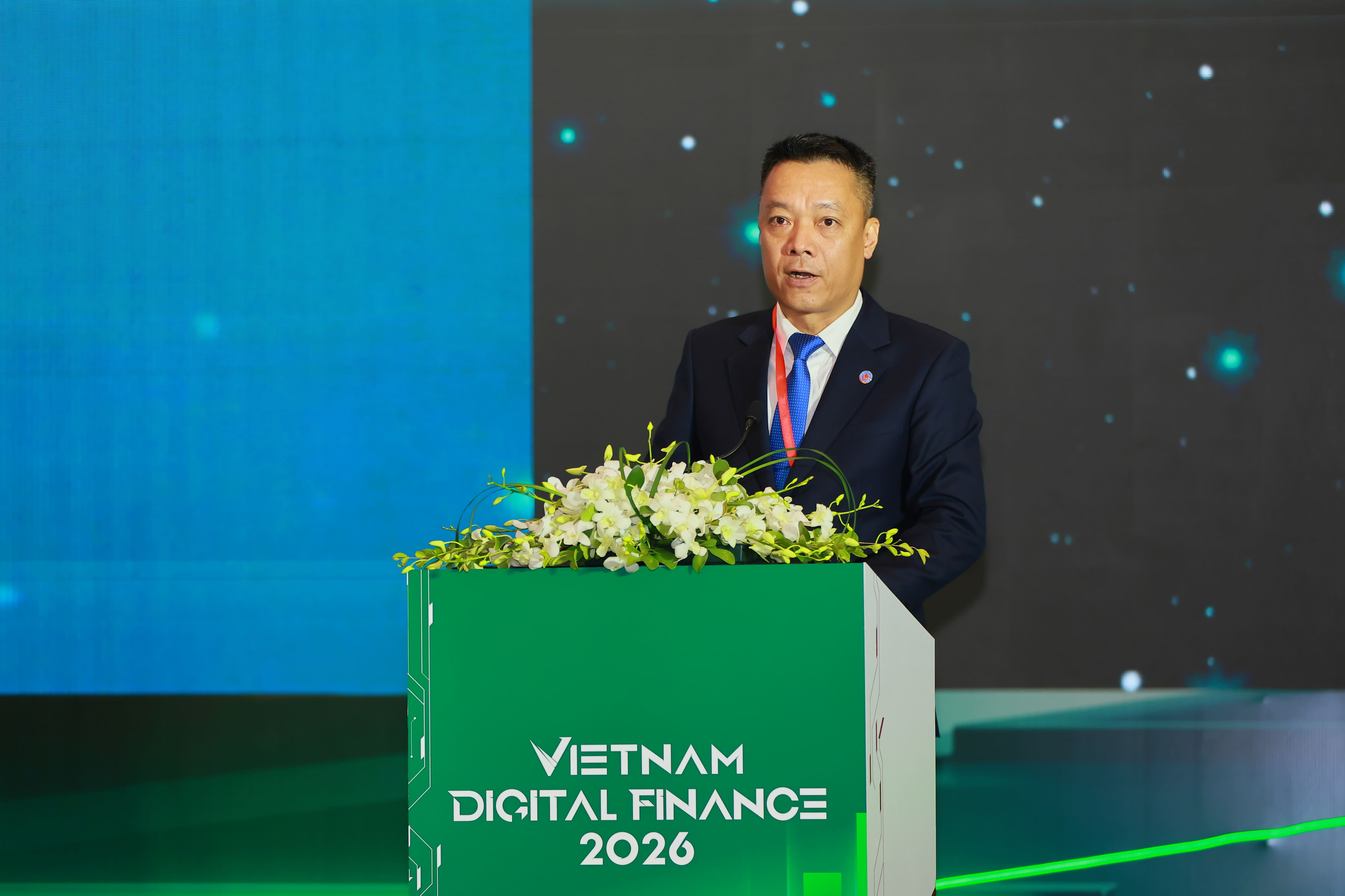 Một diễn giả tại hội nghị tài chính, tượng trưng cho các chính sách điều hành vĩ mô và tác động kinh tế.