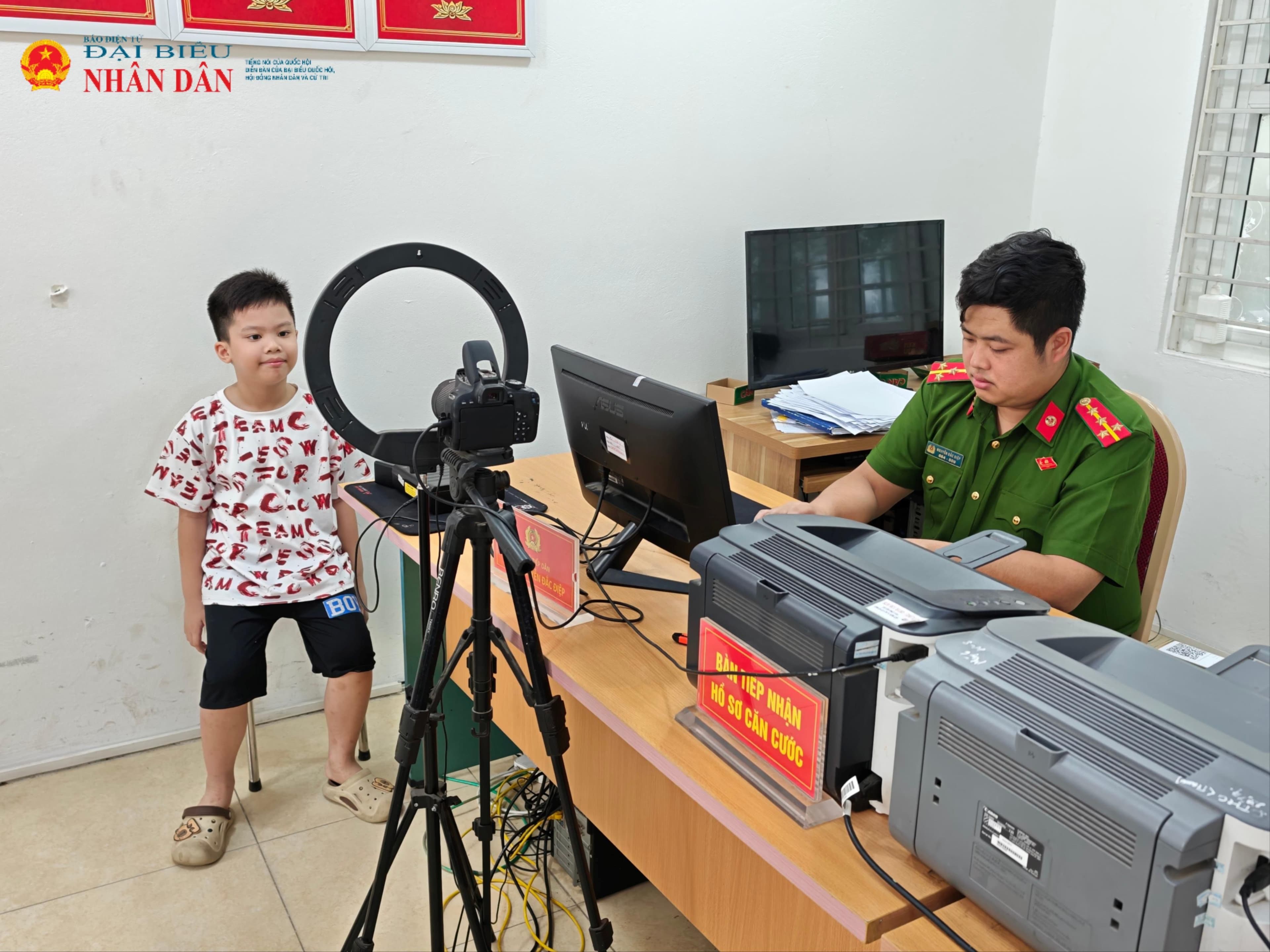 Một em bé đang làm thủ tục cấp Thẻ Căn cước tại cơ quan công an.