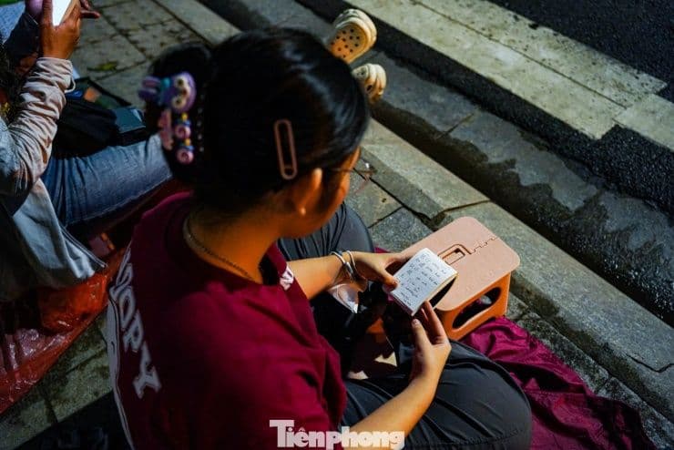 Một em nhỏ tranh thủ học bài giữa dòng người chờ đợi buổi tổng duyệt diễu binh, diễu hành tại Hà Nội.