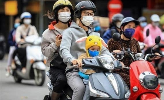 Một gia đình mặc áo ấm, đeo khẩu trang đi xe máy trên đường phố Hà Nội, thể hiện tác động của rét đậm đến đời sống thường nhật