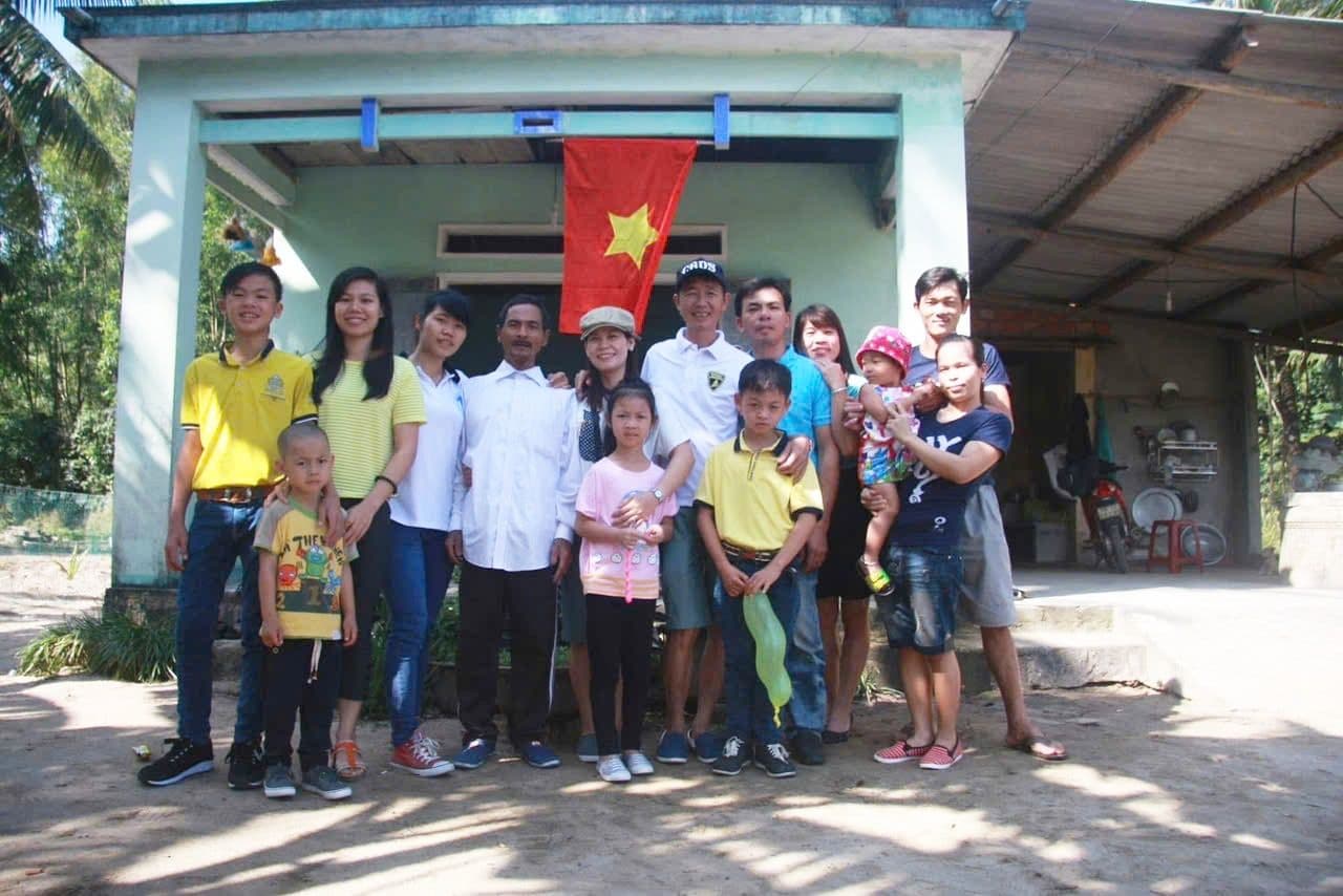 Một gia đình Việt Nam chụp ảnh trước ngôi nhà với lá cờ Tổ quốc, tượng trưng cho tiềm năng của Google Maps trong việc quảng bá văn hóa và tương tác cộng đồng.