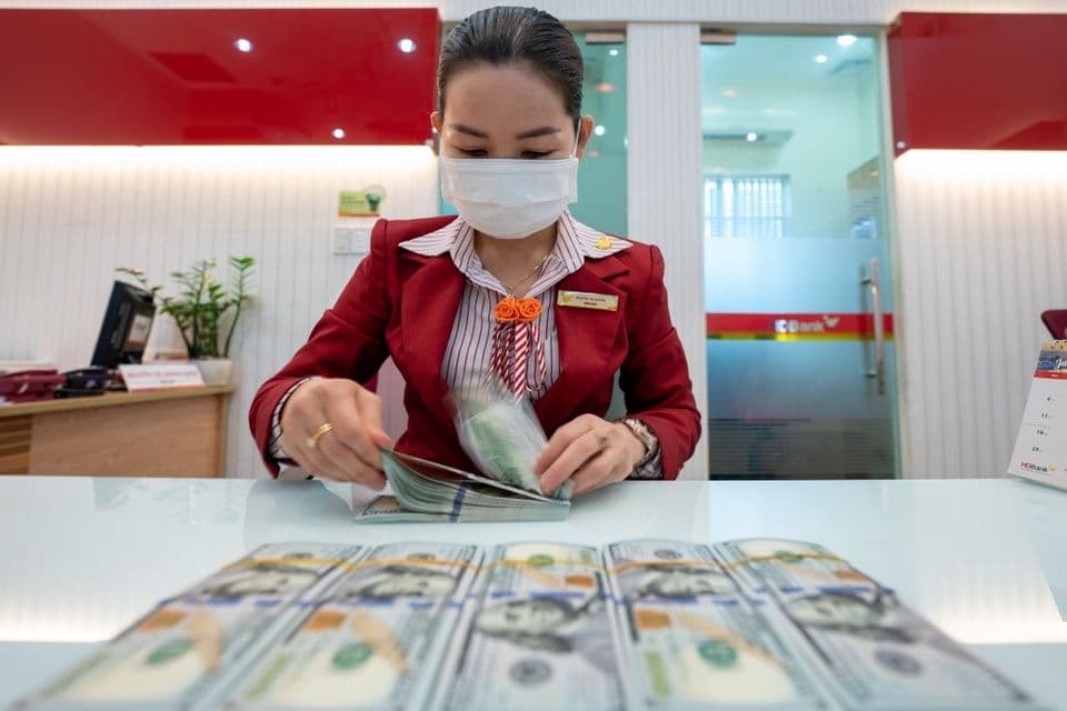 Một giao dịch viên ngân hàng đang kiểm đếm tiền đô la Mỹ, thể hiện sự biến động và giao dịch của đồng USD trên thị trường.