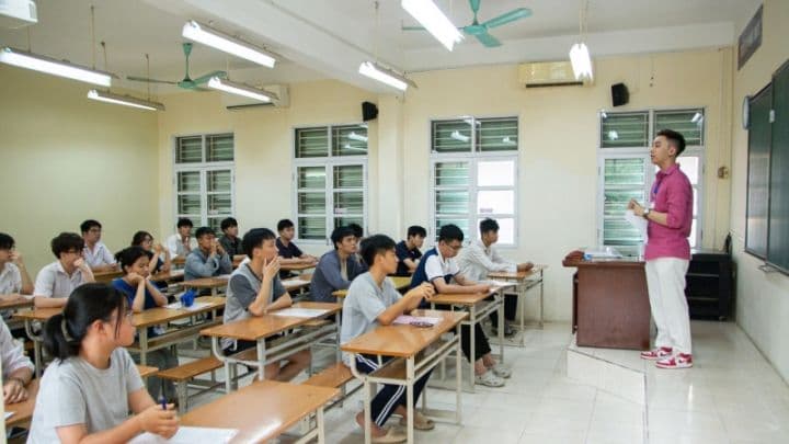 Một giáo viên đang giảng bài cho học sinh trong lớp học, minh họa môi trường giáo dục cần được đảm bảo chất lượng sau sáp nhập.