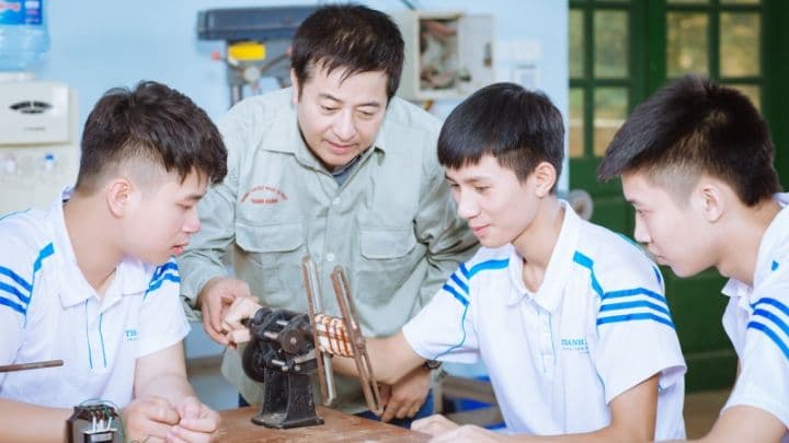 Một giáo viên hướng dẫn học sinh thực hành trong xưởng, thể hiện định hướng phát triển giáo dục nghề nghiệp và nâng cao chất lượng đào tạo.