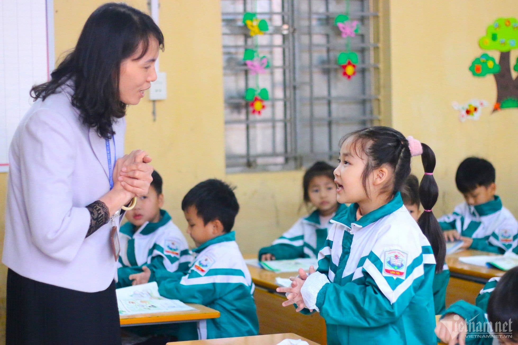 Một giáo viên tận tình hướng dẫn học sinh tiểu học trong lớp, minh họa cơ hội nâng cao chất lượng giáo dục khi cán bộ quản lý trở lại giảng dạy.