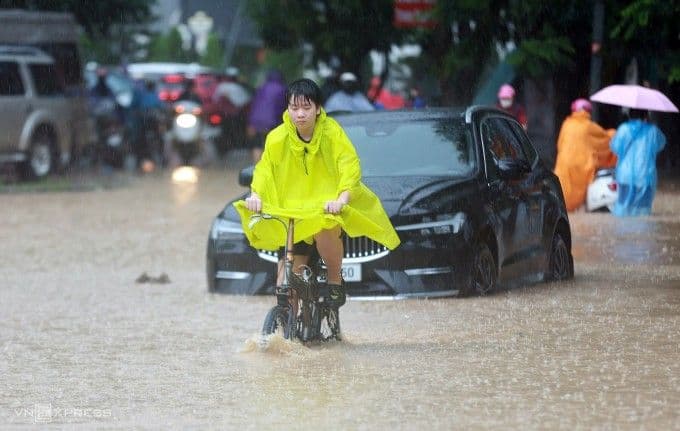 Một học sinh kiên cường đạp xe qua đường phố Hà Nội ngập sâu để đến trường.