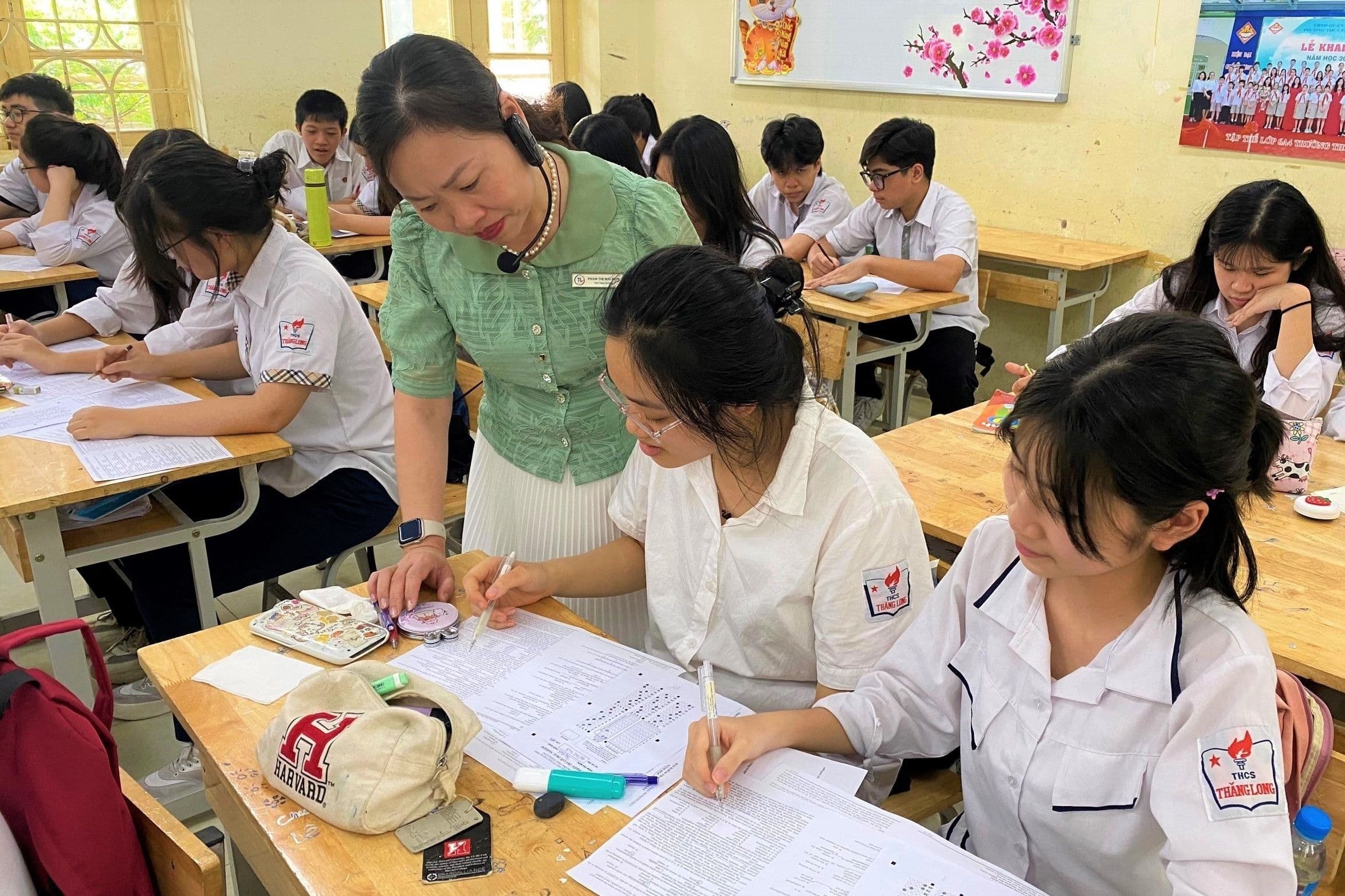 Một hiệu trưởng hoặc giáo viên hướng dẫn học sinh trong lớp học, thể hiện sự trở lại bục giảng của cán bộ quản lý giáo dục.