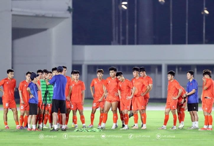 Một đội bóng đang tập trung lắng nghe huấn luyện viên trên sân tập.