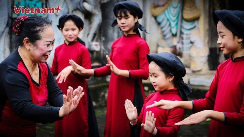 Một nghệ nhân lớn tuổi đang dạy các bé gái Hát Xoan, thể hiện sự truyền dạy văn hóa trong kỳ nghỉ lễ.