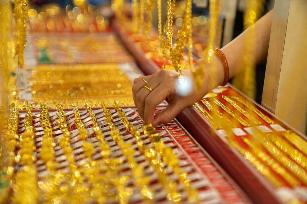 Một người đang chọn mua vàng trang sức tại cửa hàng, thể hiện sự biến động của thị trường vàng.