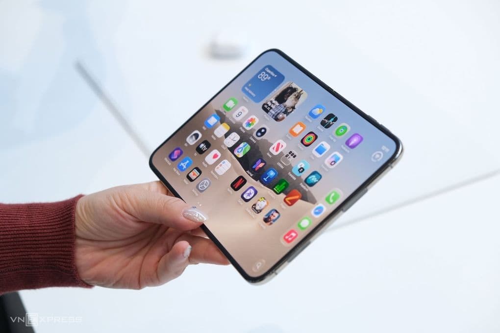 Một người đang cầm chiếc điện thoại gập iPhone Duo với màn hình hiển thị các ứng dụng, thể hiện sự sang trọng và công nghệ tiên tiến.