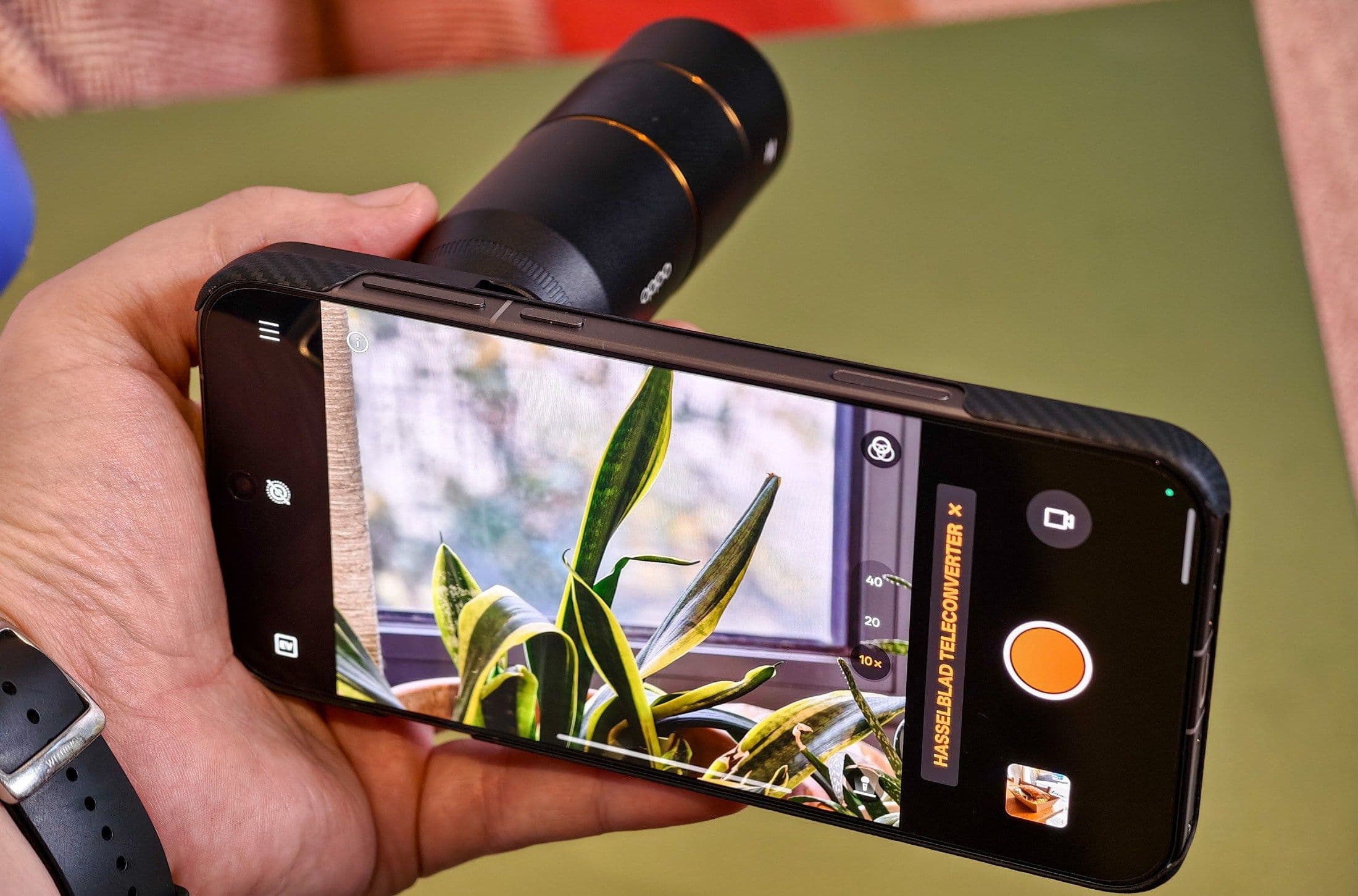 Một người đang cầm Oppo Find X9 Pro với ống kính teleconverter, sử dụng giao diện camera thông minh.