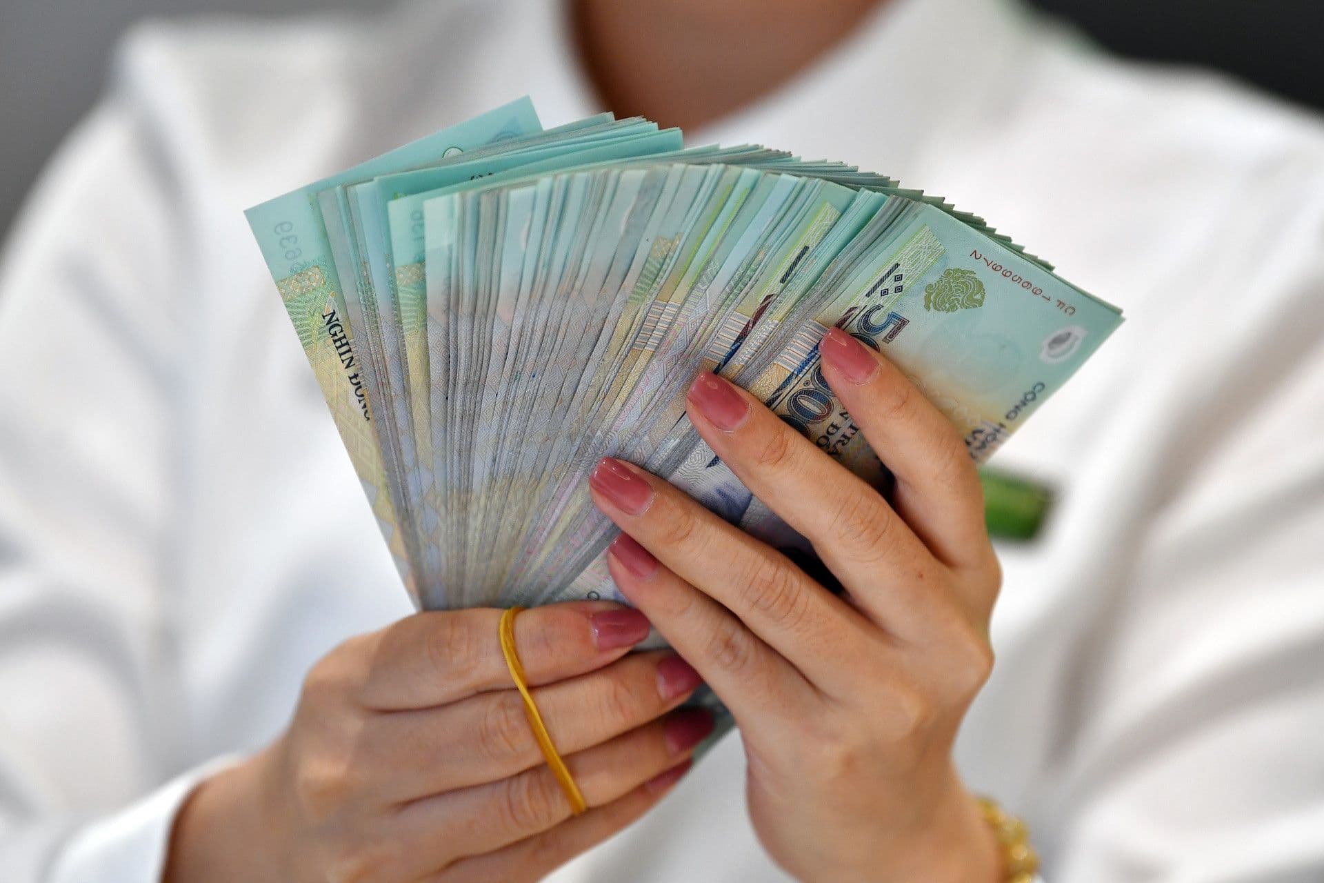 Một người đang cầm xấp tiền đồng Việt Nam, tượng trưng cho nghĩa vụ thuế và các khoản nợ.