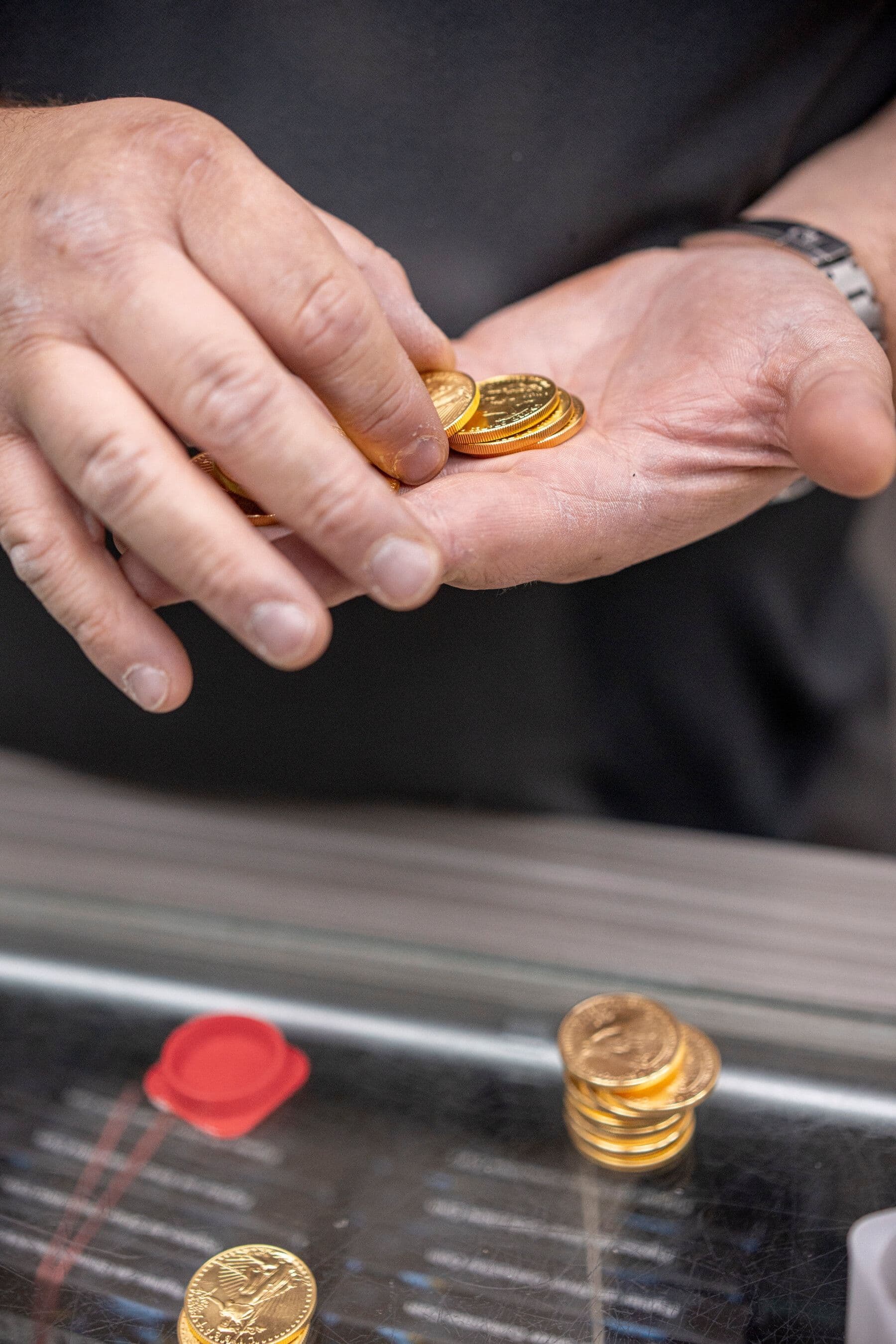 Một người đang đếm những đồng tiền vàng, biểu tượng cho giá trị tài sản và nhu cầu tiền mặt trong bối cảnh giá vàng tăng cao.