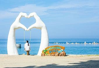 Một người đang ngồi trên xích đu tại bãi biển Wangyeong dưới trời nắng gắt.