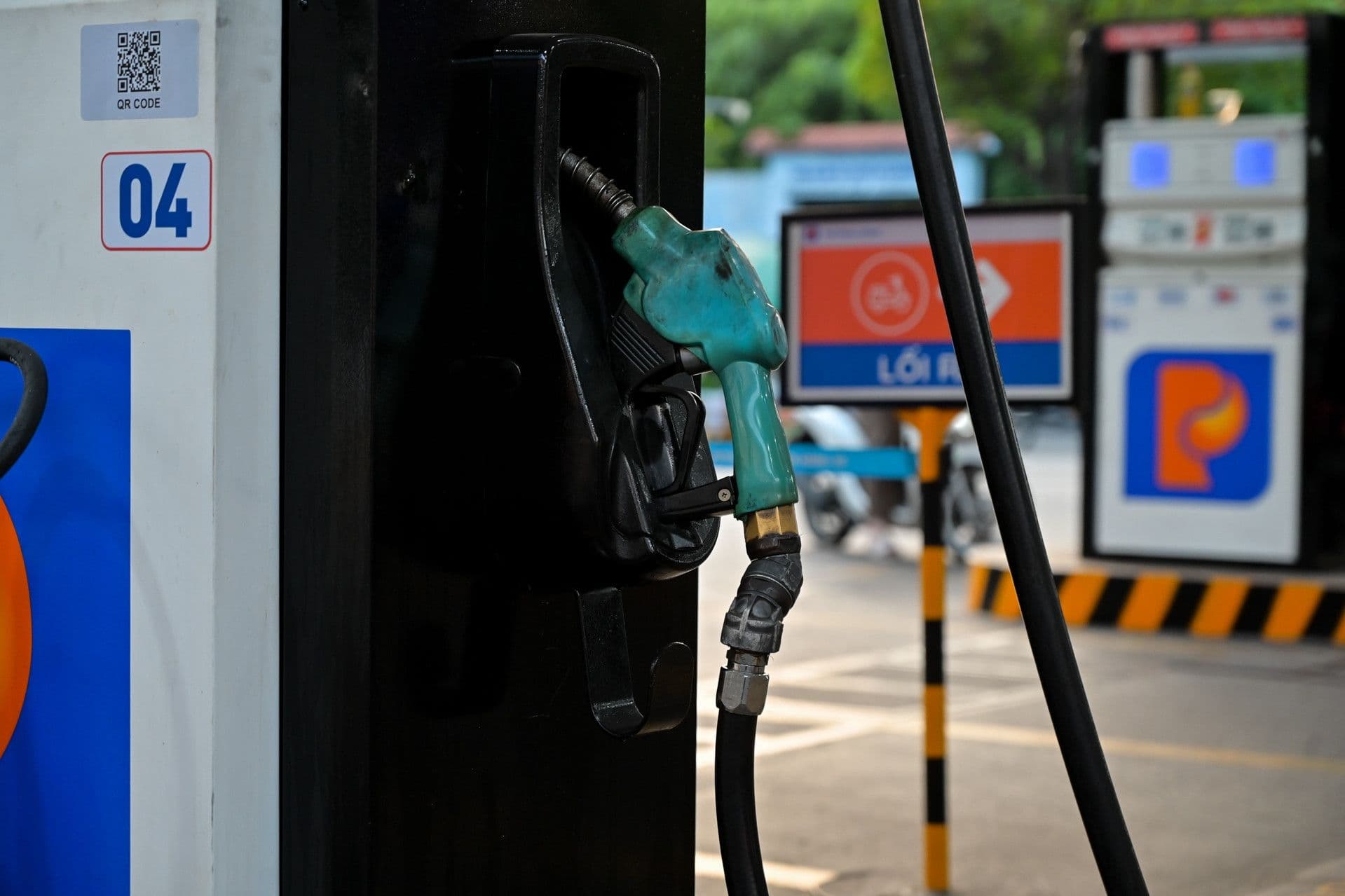 Một người đang đổ xăng vào xe máy và thanh toán, thể hiện áp lực giá xăng dầu tăng cao đối với người tiêu dùng.